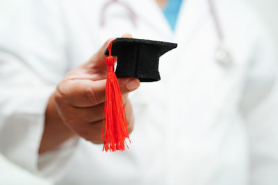 Midsection of woman holding mortarboard