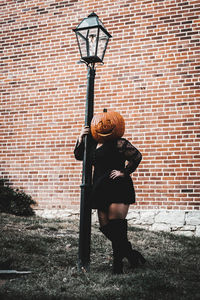 Woman with umbrella standing against brick wall
