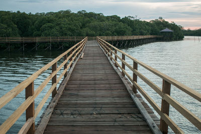 Wooden footbridge over water against sky