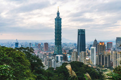 Modern buildings in city against cloudy sky