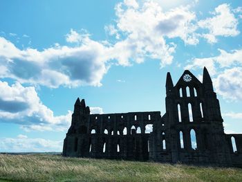 Low angle view of old ruin on field against sky