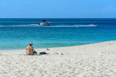 Rear view of men sitting on beach