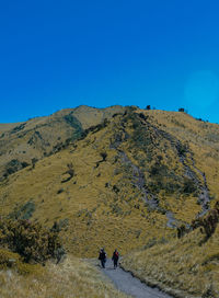 People on mountain against clear blue sky