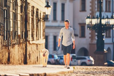 Portrait of man with dog walking in front of building