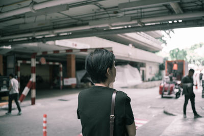 Rear view of mature woman standing on road in city