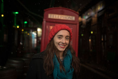Portrait of woman standing against telephone booth