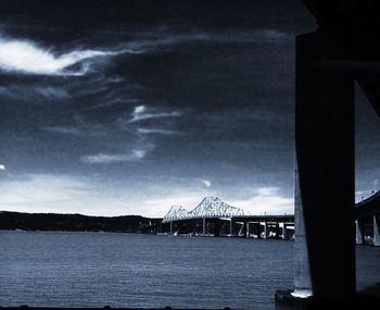 Bridge over river against cloudy sky