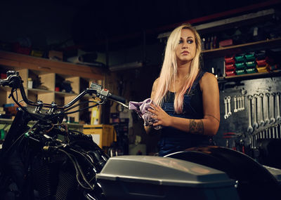 Young woman standing by motorcycle at workshop