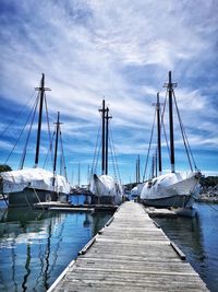 Sailboats moored in sea against sky