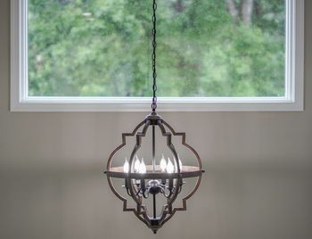 Close-up of illuminated lighting equipment hanging against window at home