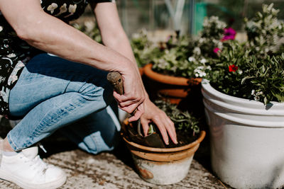 Midsection of man sitting on potted plant