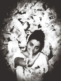 Portrait of young woman standing against wall