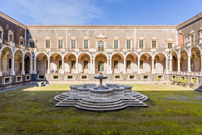 Fountain in front of historical building against sky