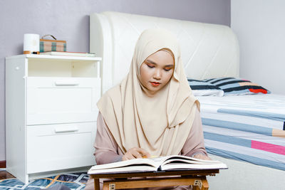 Young woman sitting on table at home