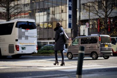 Woman with umbrella on road in city