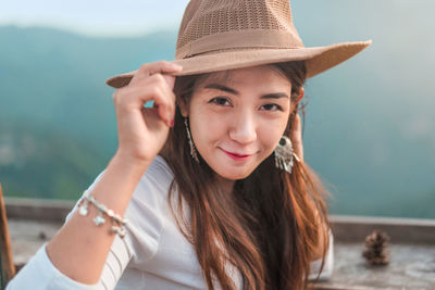 Portrait of smiling woman wearing hat standing outdoors