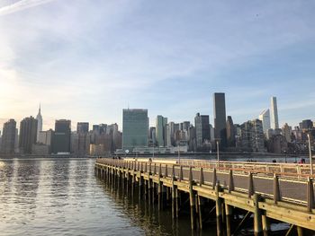 Modern cityscape by river against sky