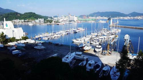 Sailboats in sea by cityscape against sky