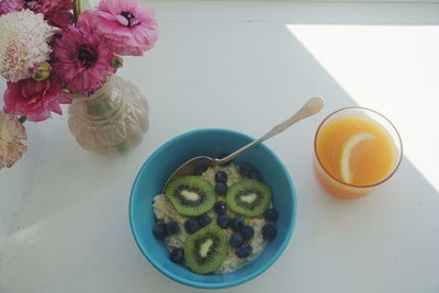High angle view of oatmeal with juice by flower vase on table