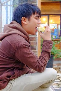 Good looking asian man wearing a corduroy jacket eating some food