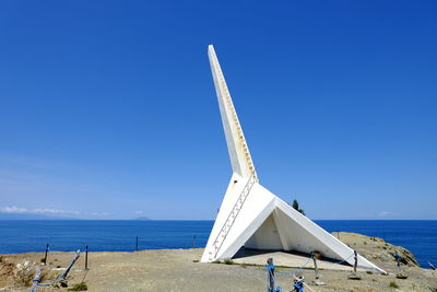 Lifeguard hut on beach against clear blue sky