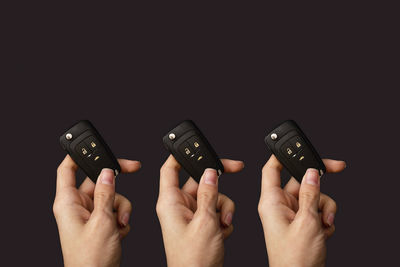 Cropped hands using mobile phone against black background