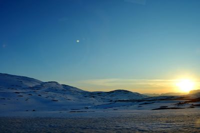 Scenic view of frozen lake against clear sky during sunset