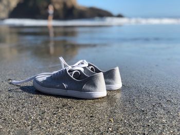 Close-up of shoes on sand at beach