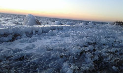 Frozen sea against sky during sunset