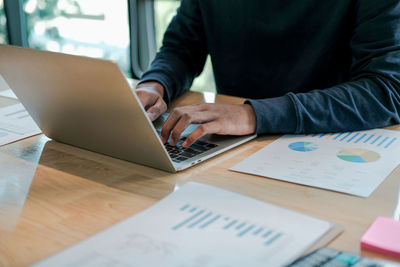 Midsection of businessman working at laptop on table in office 