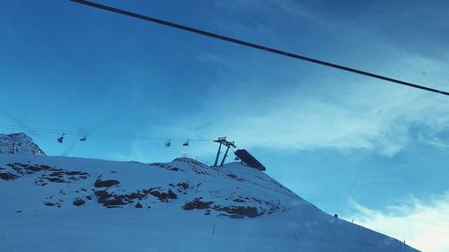 Low angle view of snowcapped mountain against blue sky