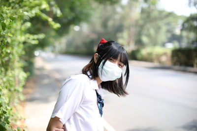 Portrait of young woman wearing mask standing outdoors