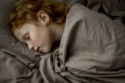 Girl with red hair sleeping in bed at home