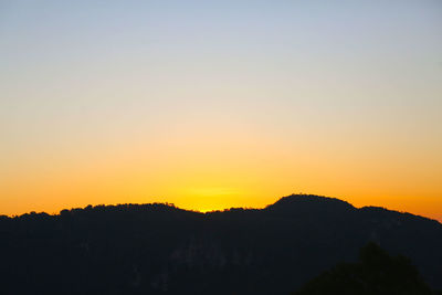 Scenic view of silhouette mountains against orange sky