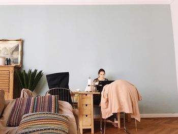 Full length of man sitting on table at home