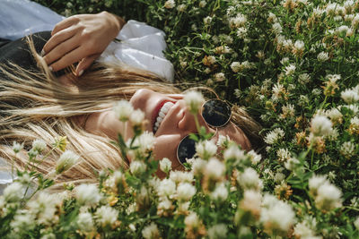 Happy woman lying on uncultivated meadow of wildflowers