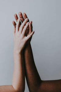 Cropped hands of women against gray background