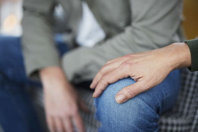 Female hand touching man's knee