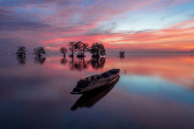 Boat in lake against sky during sunset