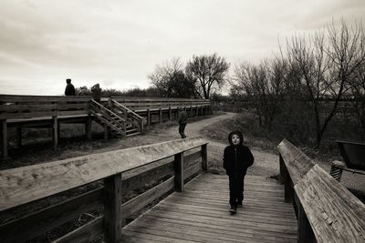 Portrait of boy walking on footbridge during winter