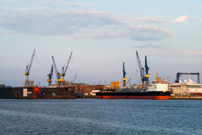 Cranes at commercial dock against sky