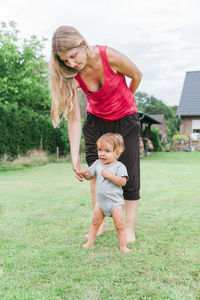 Full length of mother with daughter standing on grassy field