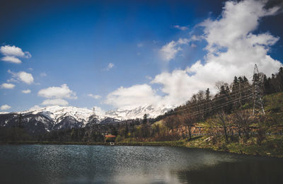 Scenic view of lake by snowcapped mountains against sky