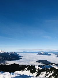 Scenic view of snowcapped mountains against blue sky