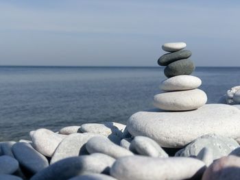 Stack of stones in sea against sky