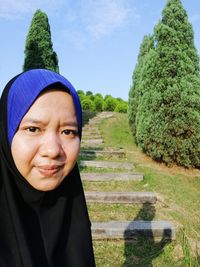 Portrait of smiling young woman against trees