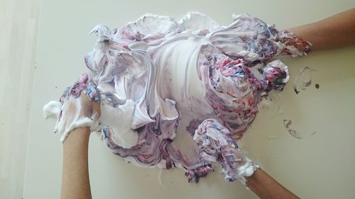 Cropped image of hands mixing shaving cream with paint over table