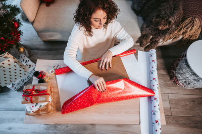 High angle view of woman wrapping christmas gift at home
