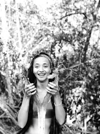 Portrait of smiling young woman standing against trees