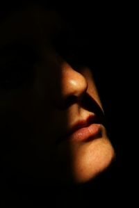 Close-up of young woman against black background